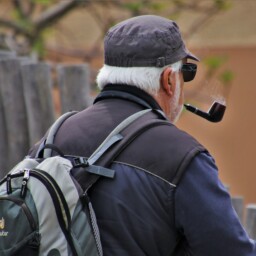 senior z fajką i plecakiem